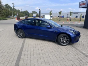 Niebieska Tesla Model 3 – ujęcie przodu na parkingu w dzień