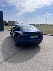 Tesla Model 3 – widok tyłu pod kątem na utwardzonym parkingu
